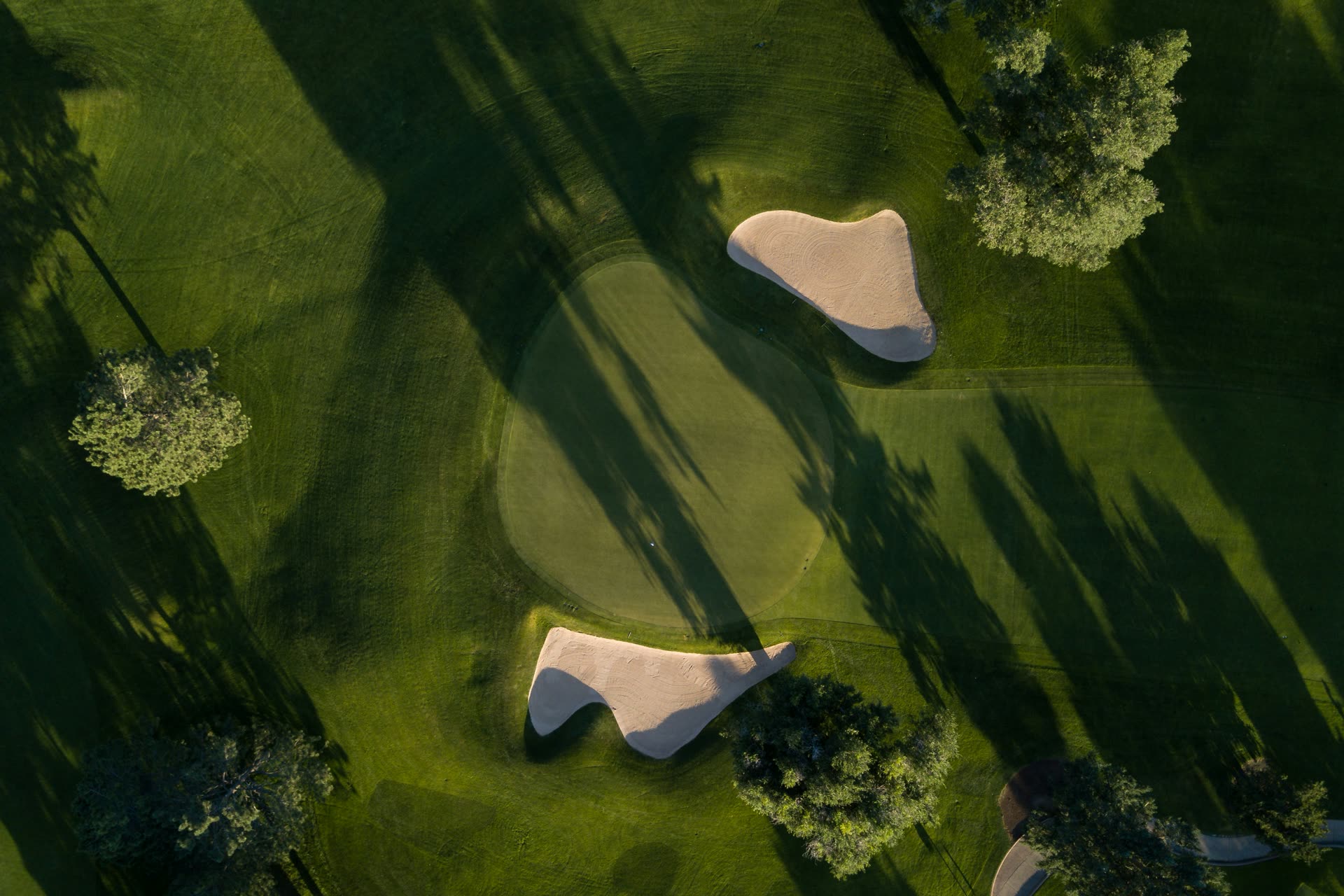 Aerial view of a green and bunkers in shadow